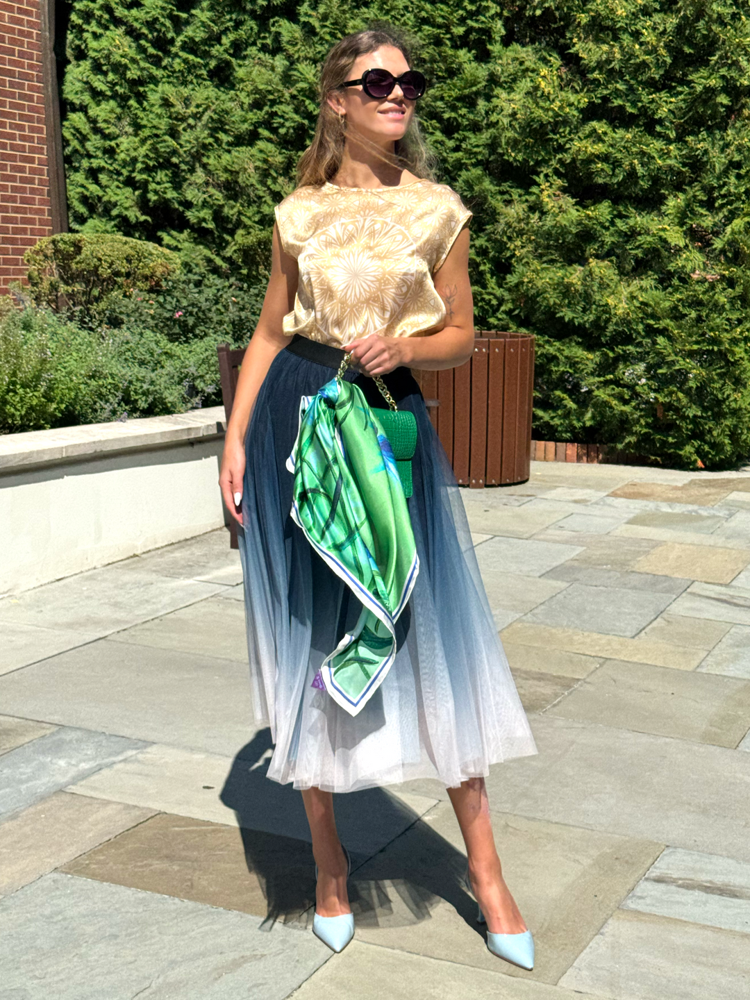 Model Wearing Cornflower Dream Designer Pure Silk Scarf In Green Royal Blue on The Handle of Her Green Purse, Paired With  Alesia C. Serenity Mandala Silk Blouse And Blue White Ombre Skirt. Wearable Art by Lake Forest, Illinois Based Artist and Fashion Designer Alesia Chaika AlesiaC.com