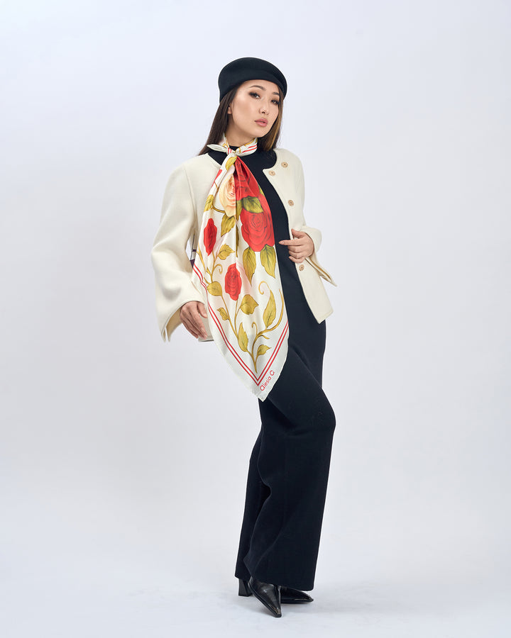 Woman wearing a floral scarf, beige coat, black pants, and black beret on a white background.  Red Rose Garden Silk Scarf - Bright Red and Cream Ivory - Alesia C. Floral Collection. AlesiaC.com
