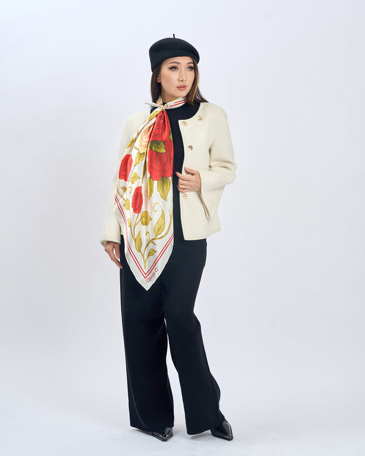 Woman wearing a floral scarf, beige coat, black pants, and black beret on a white background.  Red Rose Garden Silk Scarf - Bright Red and Cream Ivory - Alesia C. Floral Collection. AlesiaC.com